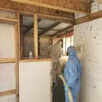 Installer applying spray foam insulation inside a framed building